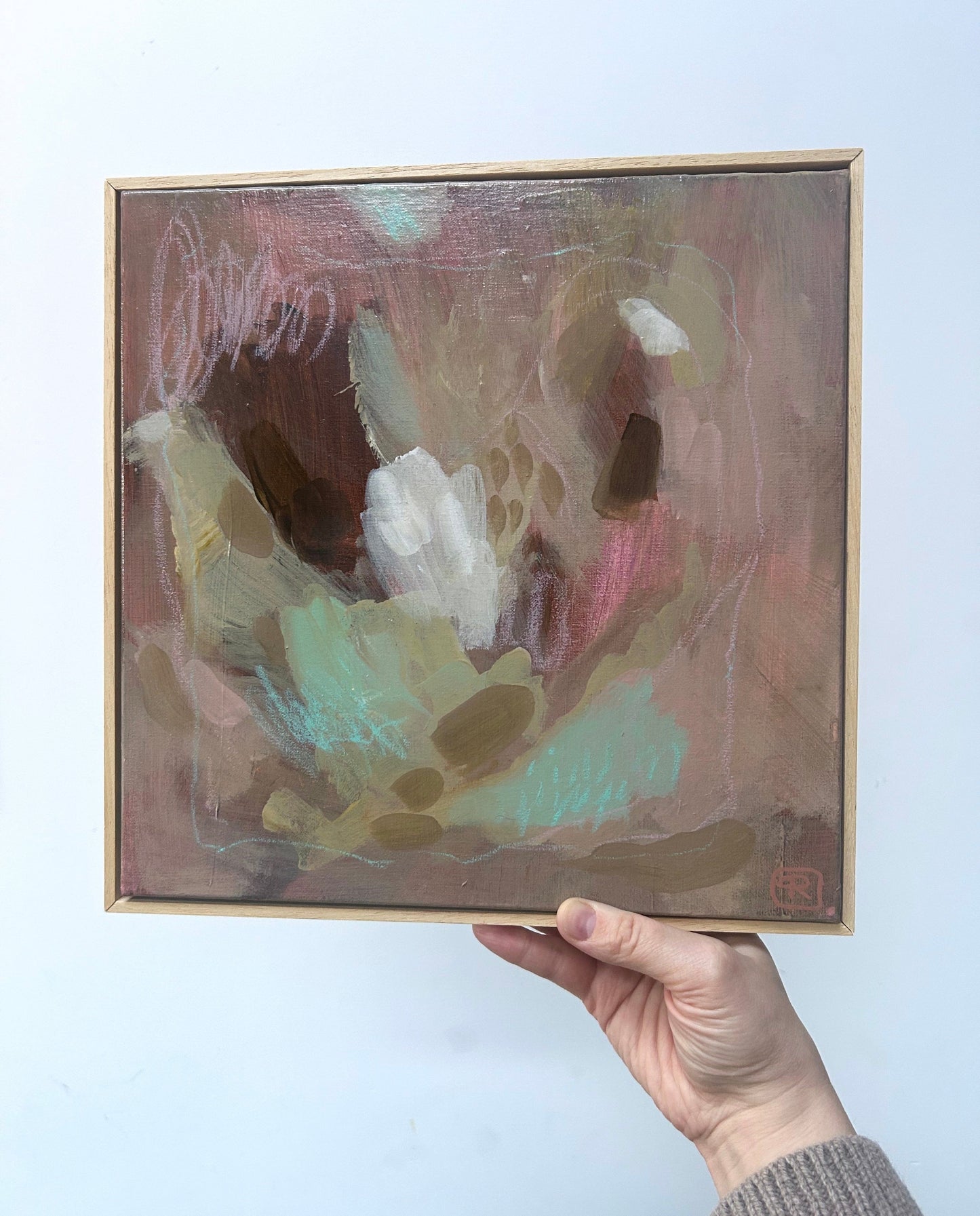 Abstract earthy tones original painting by Ruta Puidokaite held by a hand against a light background created.